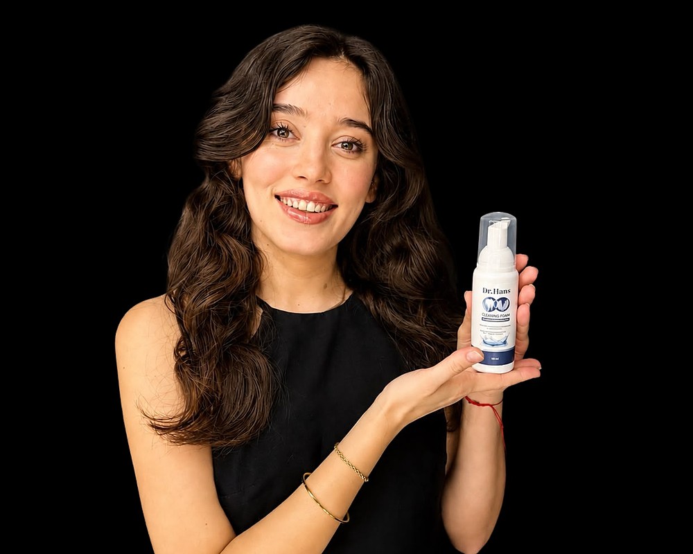 Woman holding a Dr.Hans foam bottle on a black background