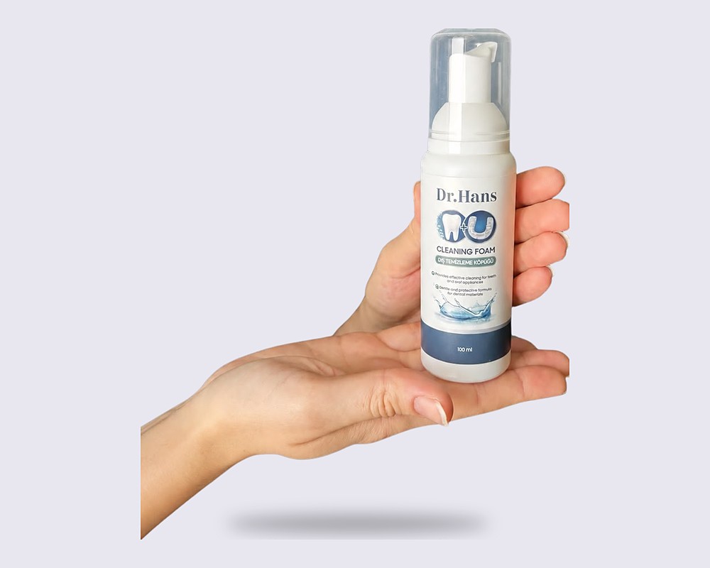 Hand holding a Dr.Hans foam bottle on a light background